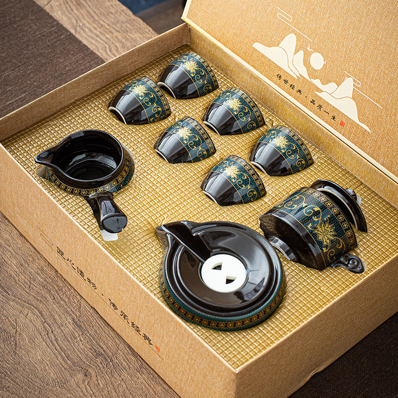 Tea set with black and gold design in a decorative box on a wooden surface