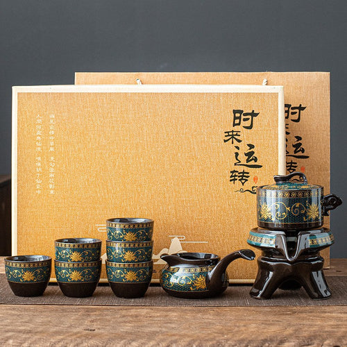 Tea set with four cups and a pot in front of a wooden box with calligraphy on a wooden surface.